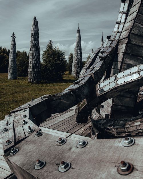 Free Artistic wooden towers in a lush, green outdoor setting under a moody sky. Stock Photo