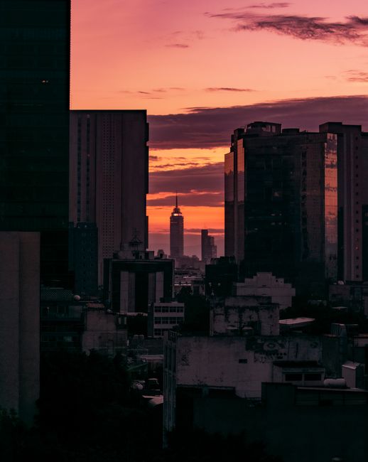 A stunning sunset view of the Ciudad de México skyline with Torre Latinoamericana framed by urban architecture.