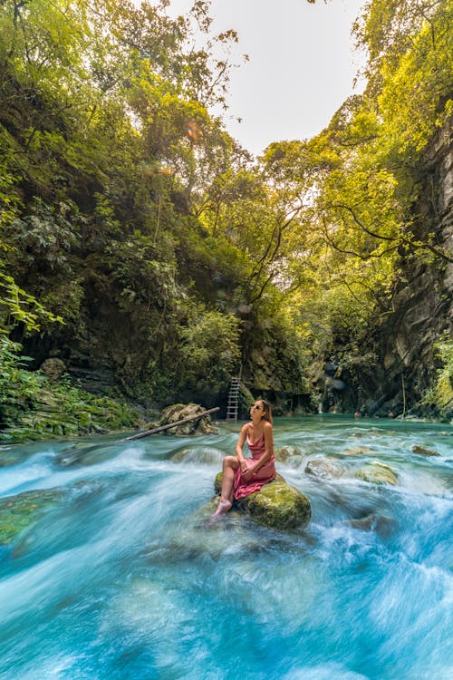 Woman in Pink Dress Sitting on a Rock