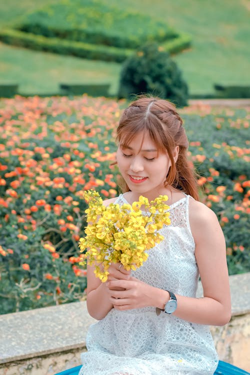 Free Woman Wearing White Top Holding Yellow Petaled Flowers Stock Photo