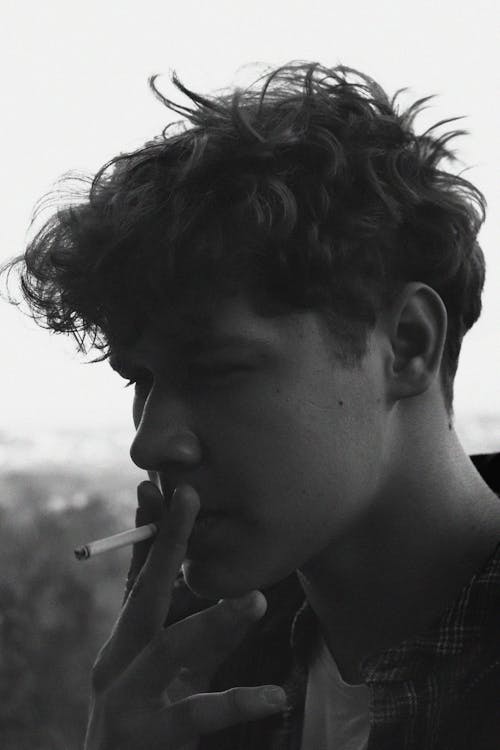 Man Smoking Cigarette in Grayscale Photography