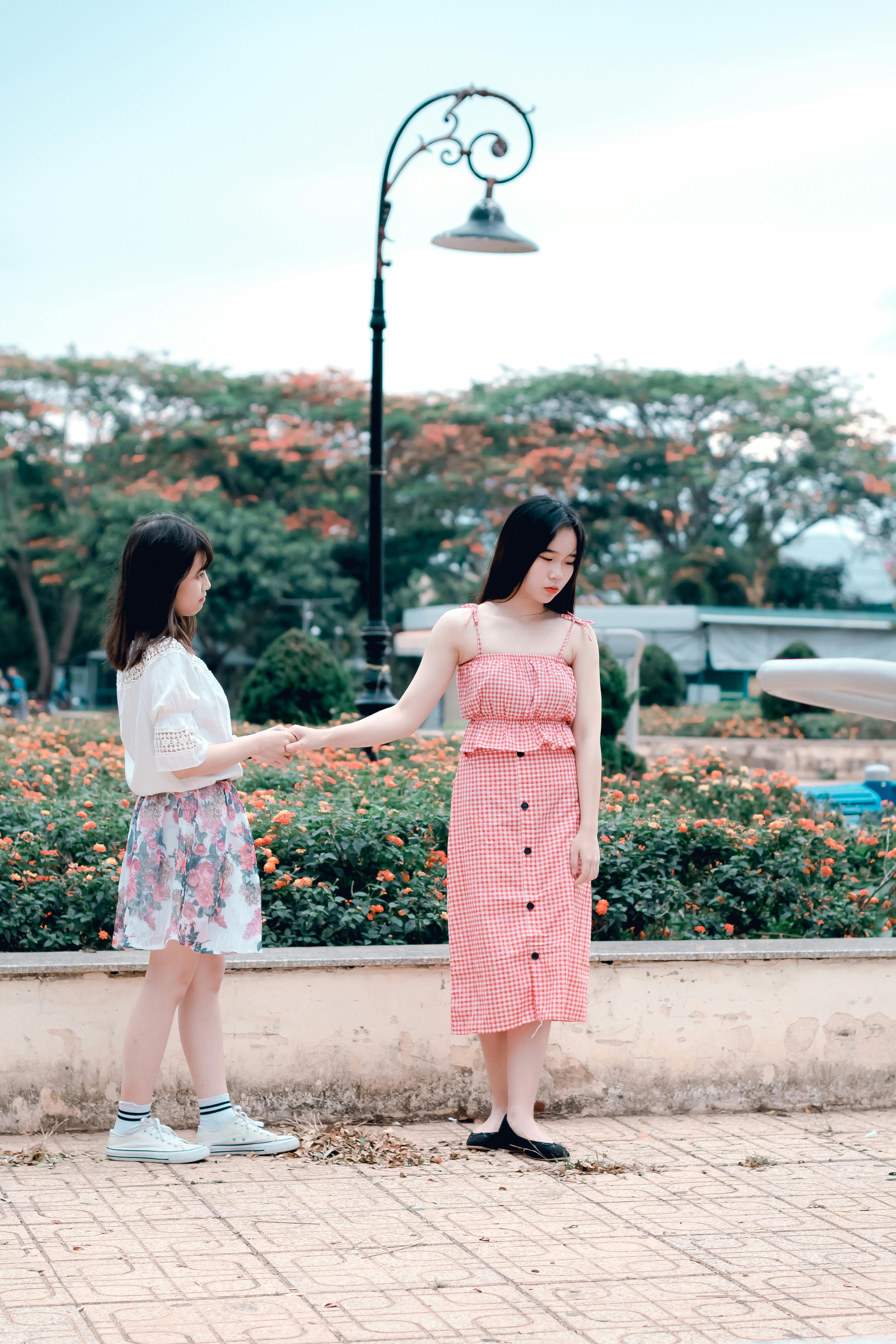 two women holding hands under green metal post lamp