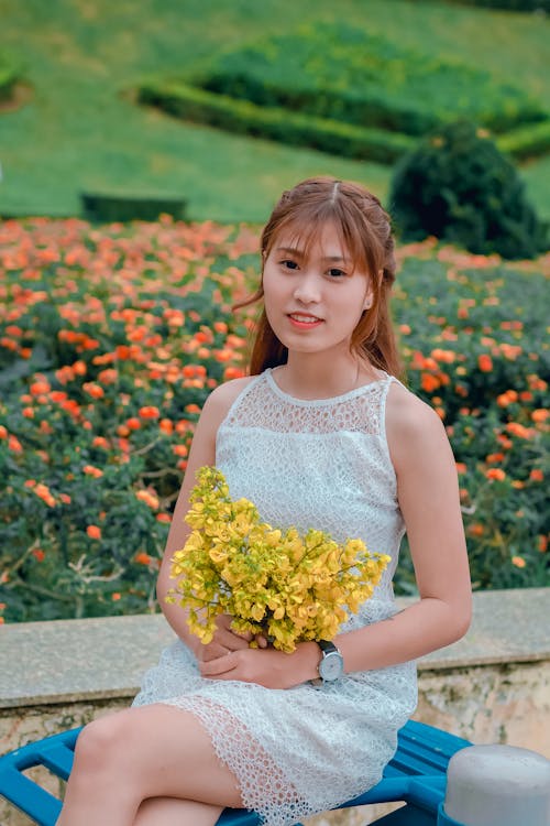 노란색 꽃의 꽃다발을 들고 드레스를 입고 여자의 초점 사진
