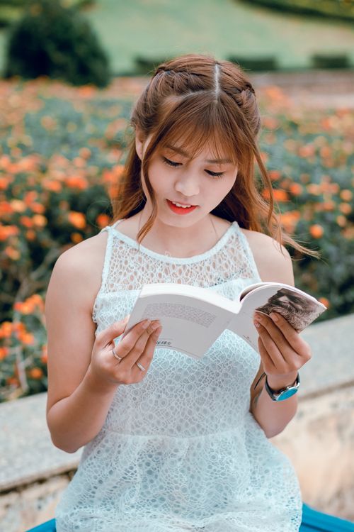 Free A young woman enjoying a book outdoors surrounded by flowers and greenery. Stock Photo