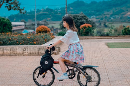 Woman Riding Bicycle Overlooking Orange Flowers and Hills