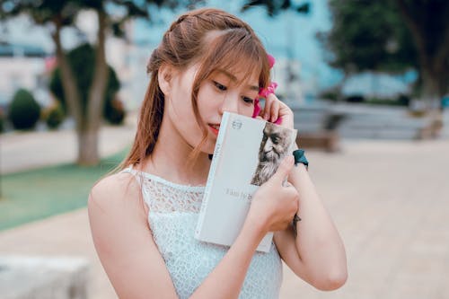 Woman Wearing White Sleeveless Top Holding Book