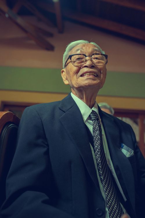 Free Charming elderly man in formal wear smiling warmly indoors. Stock Photo