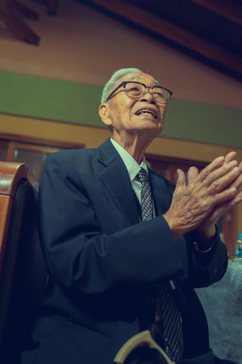 Free Senior man clapping joyously indoors, exuding warmth and cheerfulness. Stock Photo