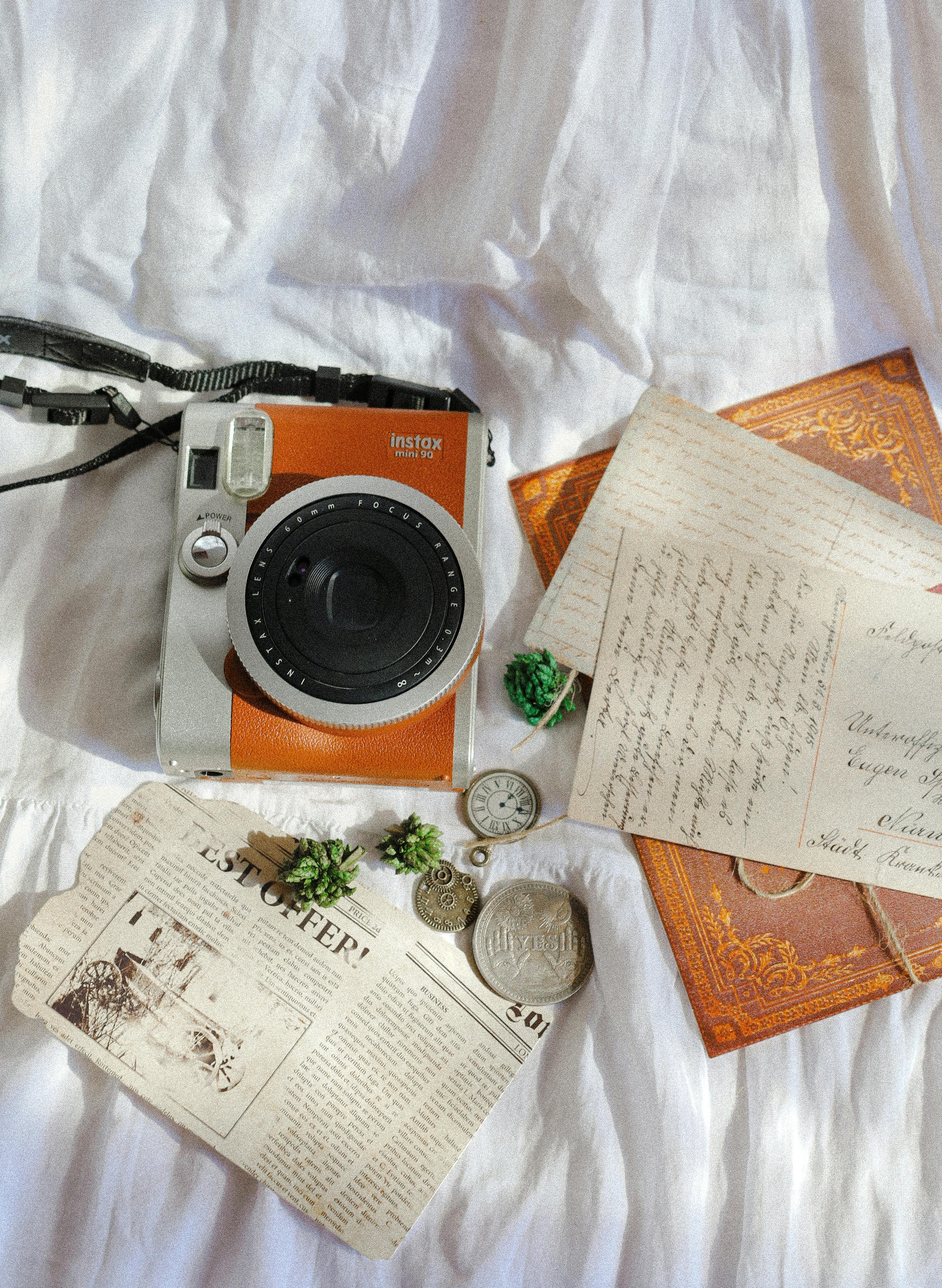 Flat lay of a vintage camera with old letters and coins on a fabric surface, ideal for nostalgic themes.