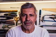 一位年长男子的肖像，背景中有工具，显得自信十足