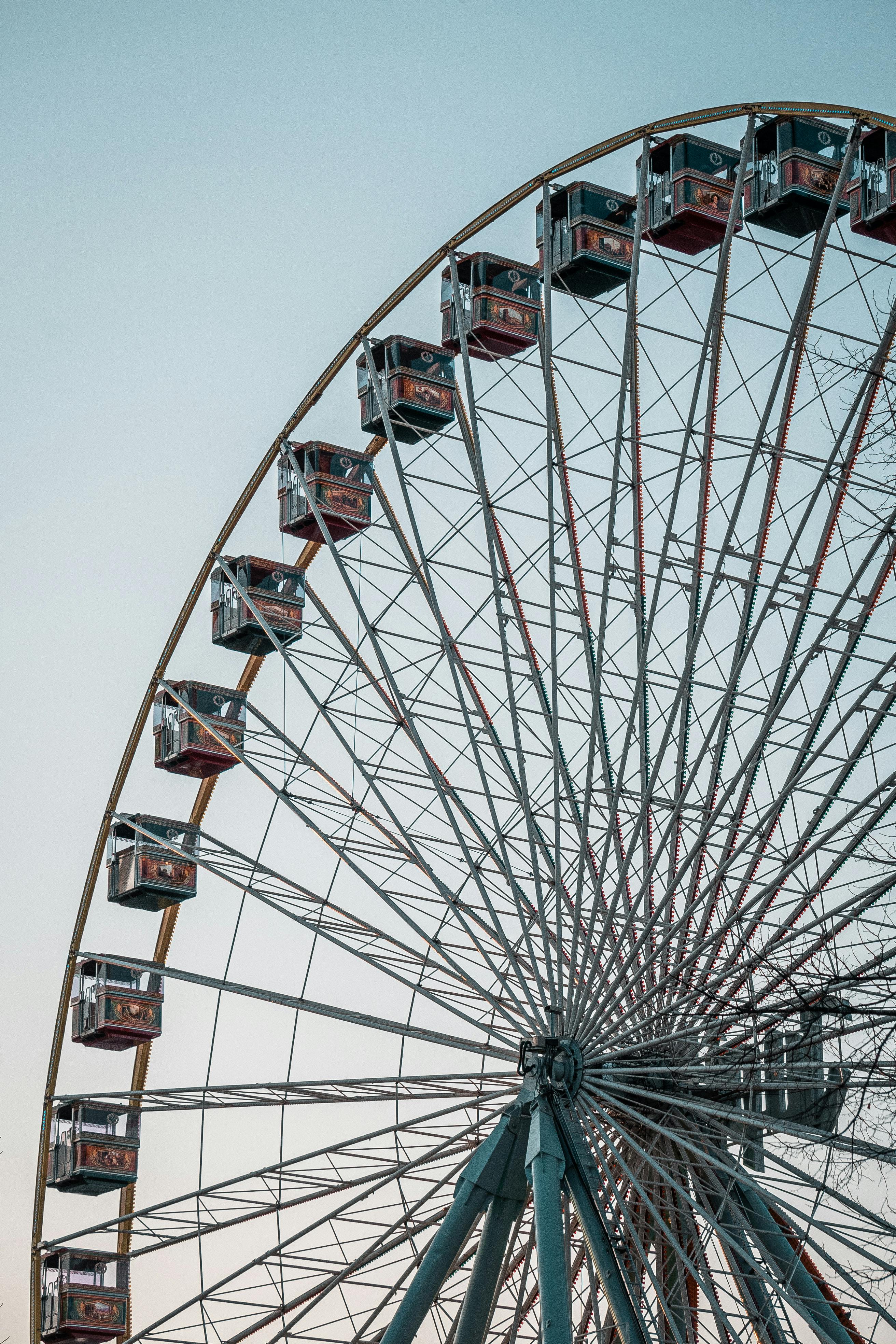 Close-up of a Ferris wheel's structure against a clear blue sky, capturing amusement park vibes.