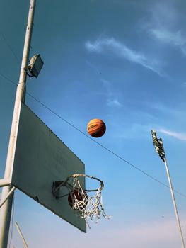 Basketball soaring through the sky towards the hoop under clear blue skies in Karachi, Pakistan.
