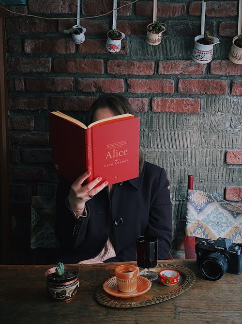 A Person in a Coat Reading a Book in a Café
