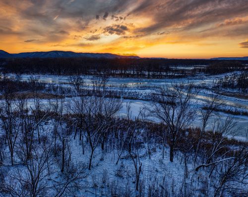 Free A breathtaking winter sunset over a snowy landscape with bare trees in Minnesota. Perfect for seasonal imagery. Stock Photo