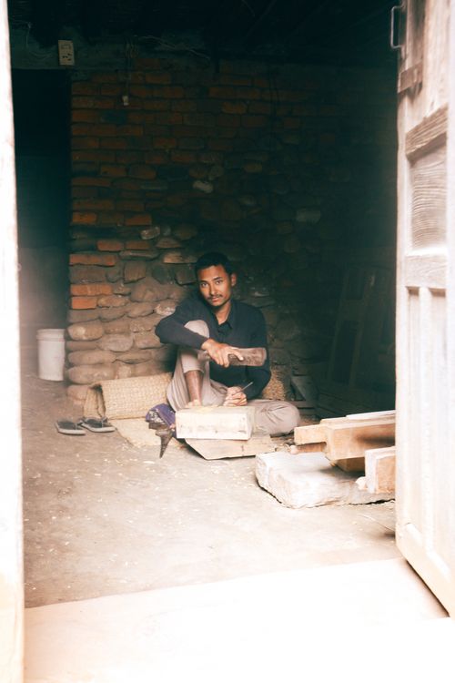 Free A man in black long sleeves sits on a mat inside a rustic room with brick walls. Stock Photo