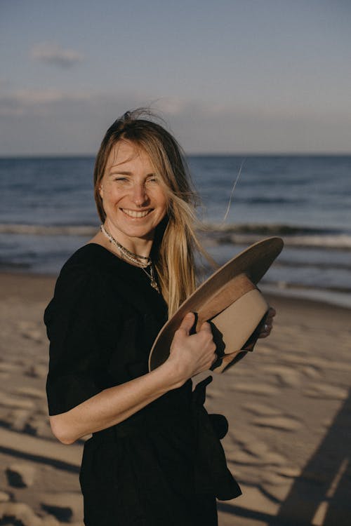 A Woman Holding a Hat at a Beach