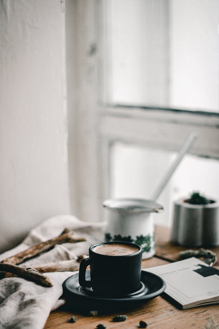 Cup Of Coffee On Messy Table By Window