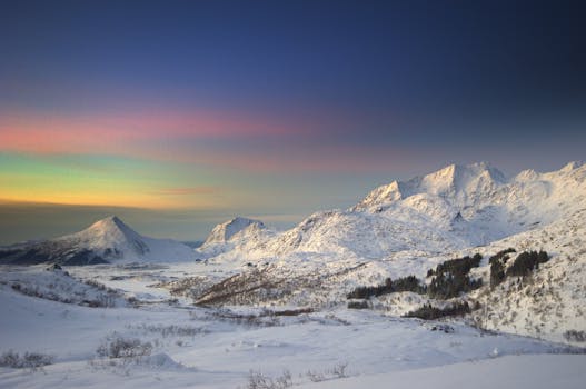 Vivid winter landscape of snow-covered mountains under a colorful sunset sky.