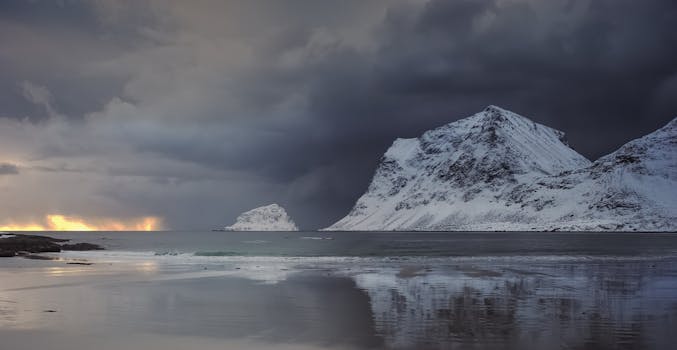 Snow-covered mountains and dark clouds create a dramatic winter landscape.
