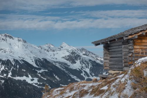 Free Scenic view of a wooden cabin in snow-covered mountains during winter. Stock Photo