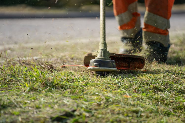 A Person Using A Grass Cutter Tool Green Grass