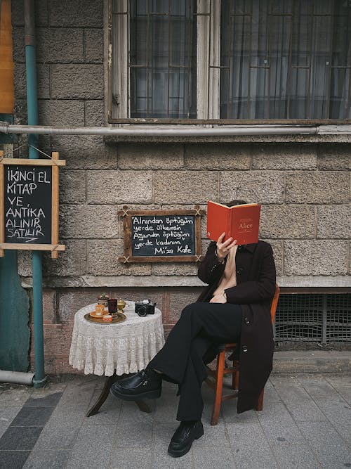 Man Wearing a Coat Reading a Book