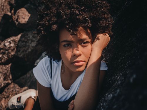 Free Close-up portrait of a thoughtful woman with afro hair outdoors, capturing natural beauty and emotion. Stock Photo