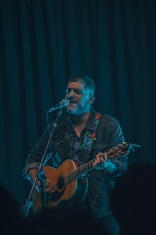 Man Playing Guitar While Singing