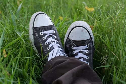 Free Close-up of classic black sneakers on vibrant grass, capturing a relaxed outdoor moment. Stock Photo