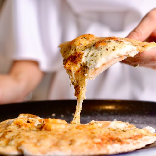 Free Close-up of a cheese pizza slice being pulled, showcasing its delicious texture. Stock Photo