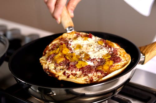 Person Cooking Pizza on a Frying Pan