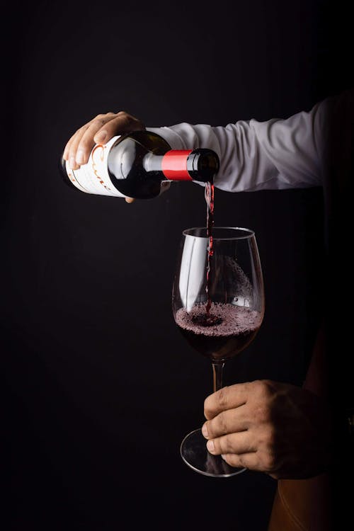 Person Pouring Red Wine in a Glass
