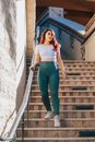 Woman in White Shirt and Blue Denim Jeans Standing on Stairs