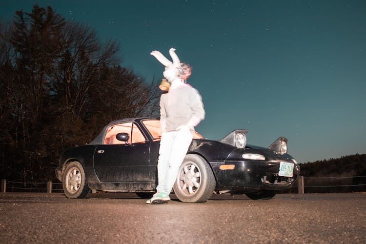 Blurred Person In Mask Leaning Against Car