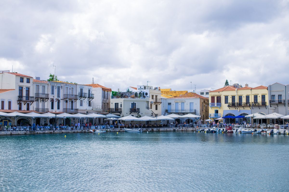 Pastel waterfront houses and moored fishing boats in the old Venetian harbor of Rethymno