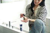 Woman in Black and White Stripe Shirt and Blue Denim Jeans Sitting on White Table