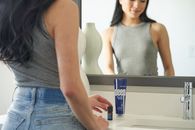 Woman in Gray Tank Top and Blue Denim Jeans Holding Blue Box