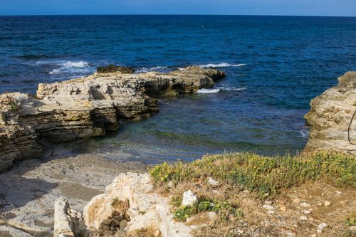 Free A tranquil seascape with rocky formations and gentle waves on a sunny day. Stock Photo