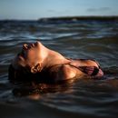 Woman in Black Bikini Top Lying on Water