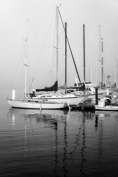 Grayscale Photo of Sailboats Docked on the Port