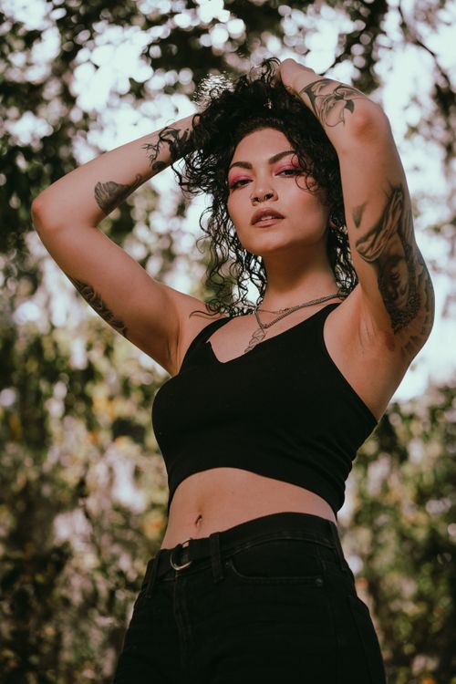 Free A fashionable woman with tattoos poses confidently in a natural outdoor setting. Stock Photo