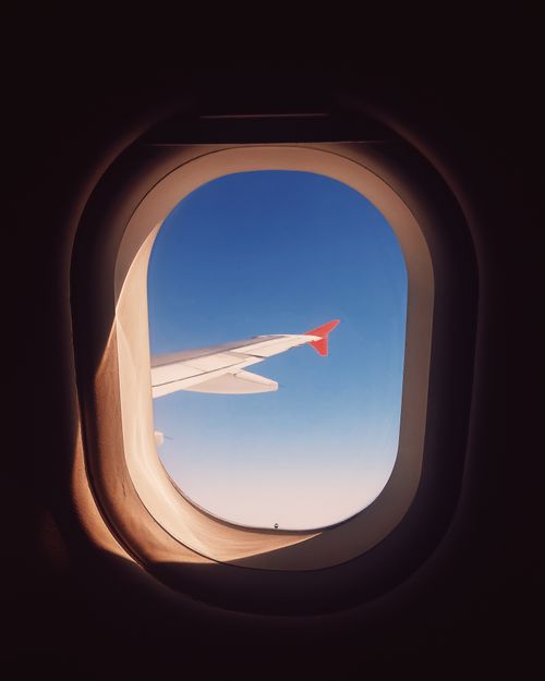 Free Capture of an airplane wing view through a window with clear blue sky. Stock Photo