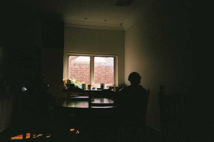 Silhouette Of People Sitting In A Dining Room Near A Window