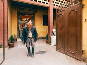 Elderly Man Walking Beside a Gate