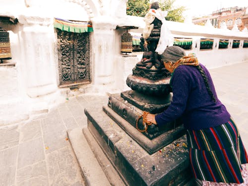A Woman in Purple Sweater Praying on a Buddha