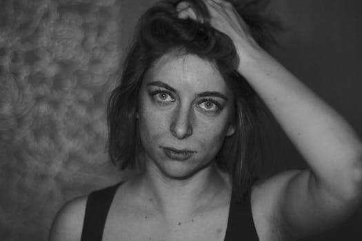 Captivating monochrome portrait of a woman with hand in hair, showcasing expressive eyes.