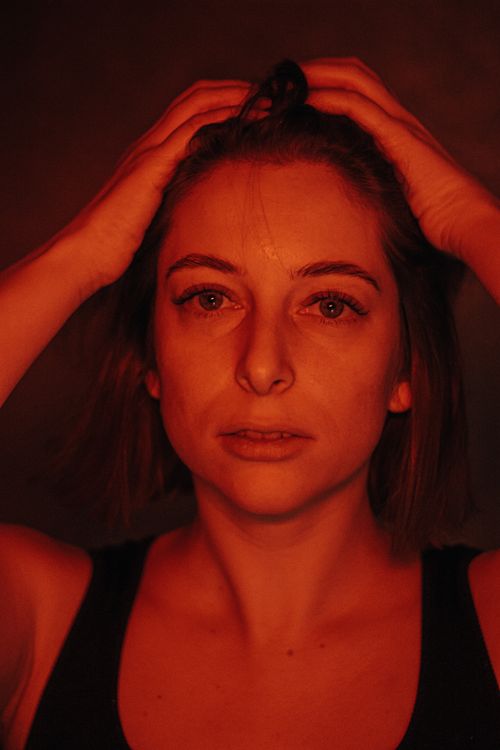 Free Intense close-up portrait of a woman with hands in hair against red lighting. Stock Photo