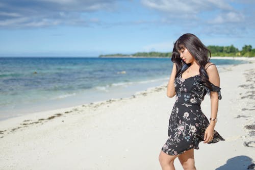 Woman in Floral Dress Standing on the Beach