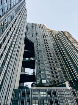 A low-angle shot of a modern skyscraper with glass facade and unique architectural design.