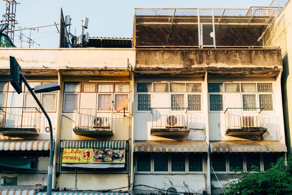 A rustic urban building facade featuring small balconies and city signage.